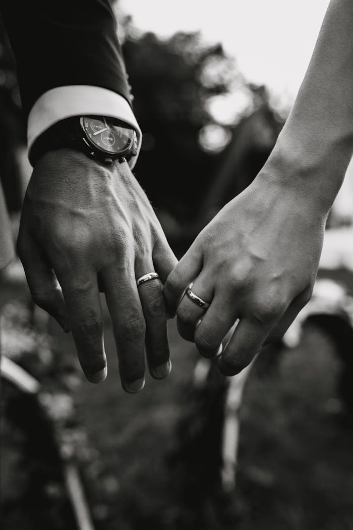 A touching black and white photograph of a couple's hands displaying wedding rings symbolizing love and unity.